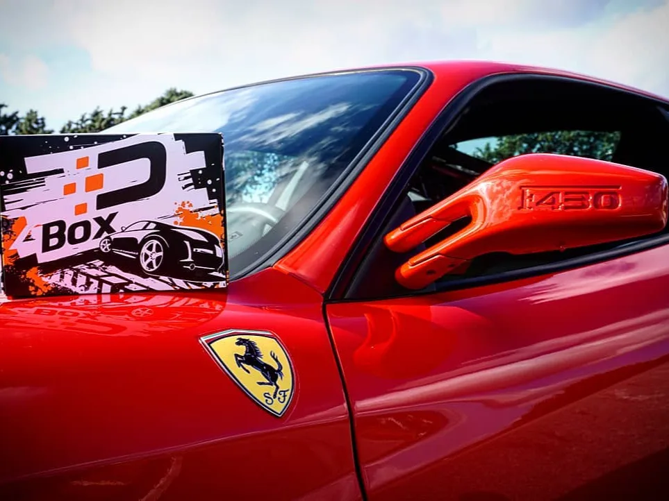Box regalo Drivemotive con voucher appoggiata su una Ferrari F430